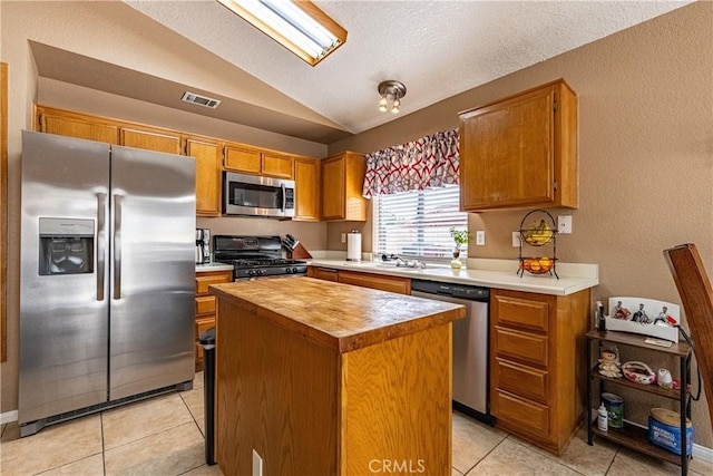 510 Monika Ct, Beaumont, CA 92223 - kitchen featuring a kitchen island, visible vents, appliances with stainless steel finishes, lofted ceiling, and light tile patterned flooring