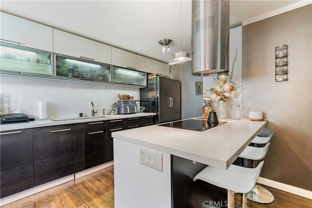 360 Obispo Ave Unit 15, Long Beach, CA 90814 - kitchen featuring black appliances, exhaust hood, a breakfast bar, a peninsula, and light wood finished floors