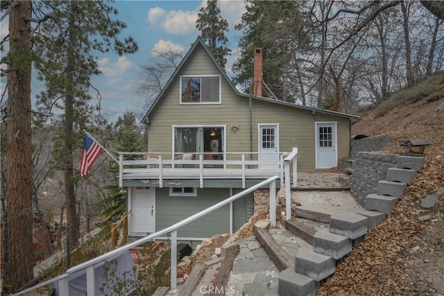 back of property with a wooden deck and a chimney