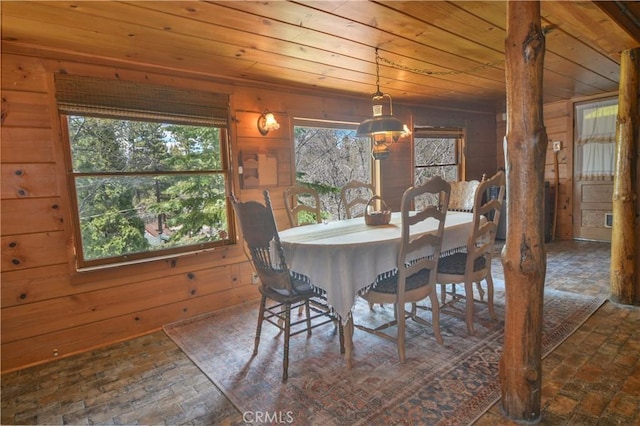 dining room featuring wooden walls, wood ceiling, and brick floor