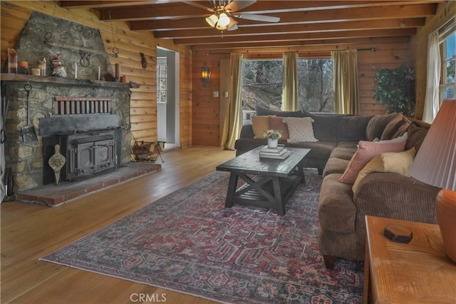 living area with a ceiling fan, wood finished floors, a healthy amount of sunlight, and beamed ceiling