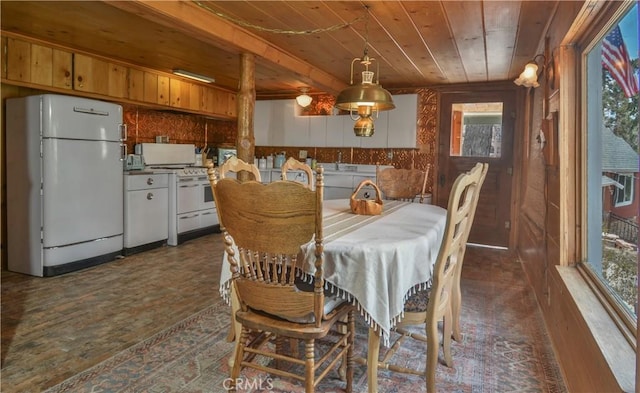dining space featuring wooden walls, wooden ceiling, and dark wood finished floors