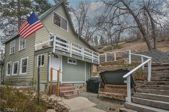 rear view of property featuring a balcony and entry steps