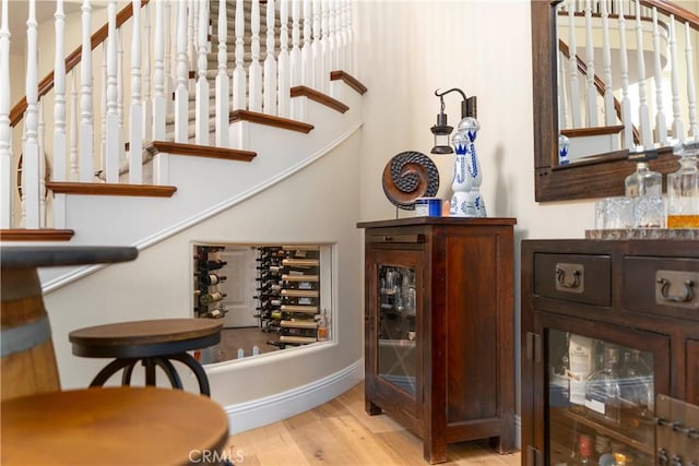 bar with baseboards, wood finished floors, and stairway
