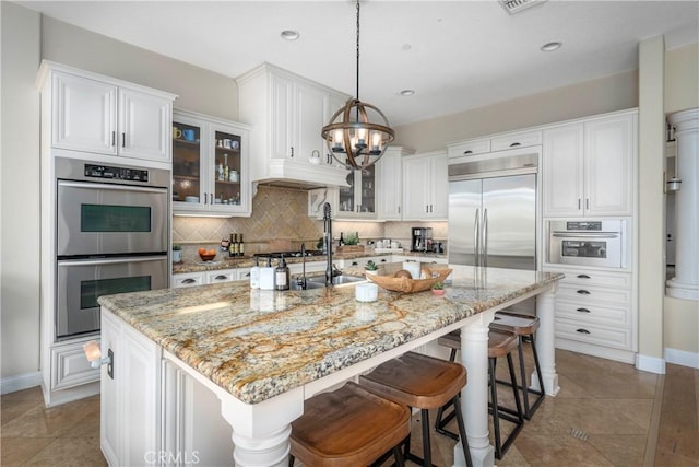 kitchen featuring stainless steel appliances, an inviting chandelier, white cabinetry, and tasteful backsplash