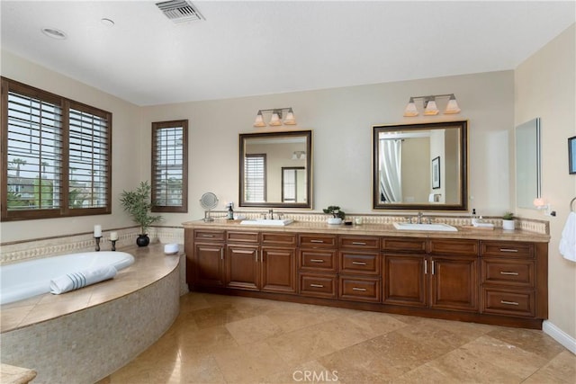 full bathroom featuring double vanity, visible vents, a sink, and a garden tub