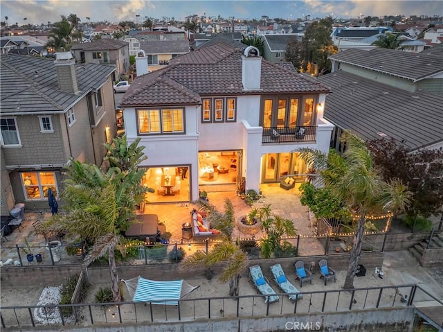 rear view of property with a patio, a chimney, a balcony, and stucco siding