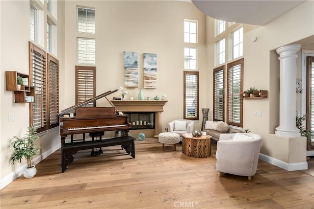 living area featuring light wood-style floors, a high ceiling, and ornate columns