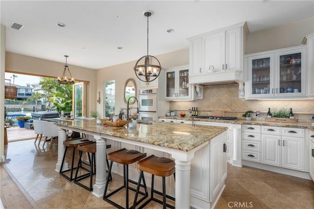 kitchen featuring white cabinets, backsplash, and a notable chandelier