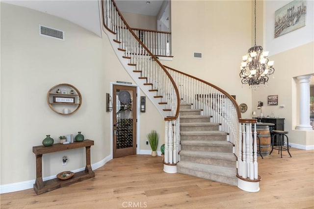 staircase with baseboards, a high ceiling, wood finished floors, and visible vents