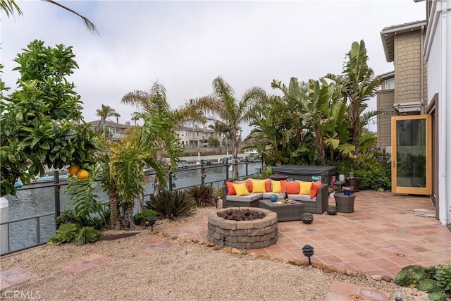 view of patio with a hot tub, fence, and a fire pit