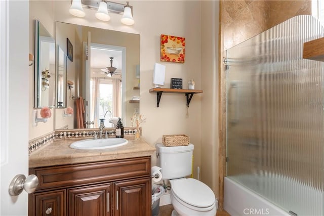 bathroom with vanity, combined bath / shower with glass door, ceiling fan, and toilet