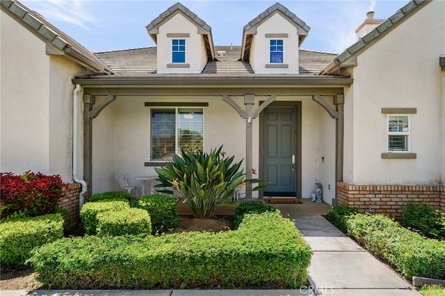 955 Union St, Cherry Valley, CA 92223 - view of exterior entry with stucco siding, brick siding, covered porch, and a tiled roof