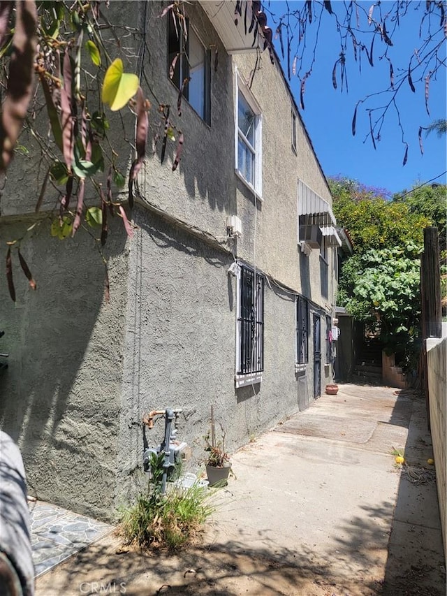 view of side of home featuring fence, a patio, and stucco siding