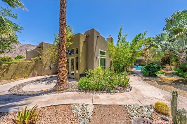 54030 Eisenhower Dr, La Quinta, CA 92253 - back of house with french doors, stucco siding, and a chimney