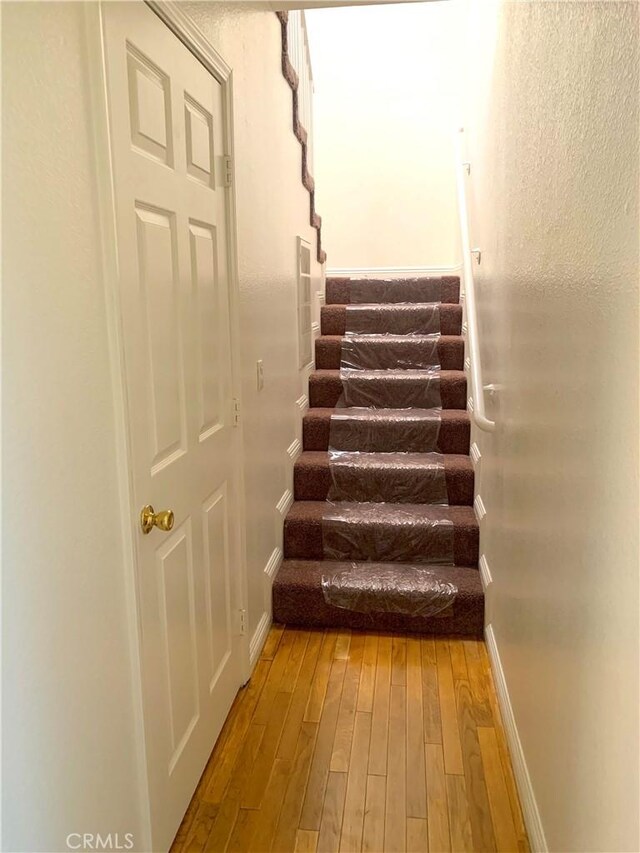 stairway featuring wood-type flooring and baseboards