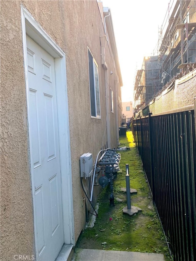 view of side of home featuring fence and stucco siding