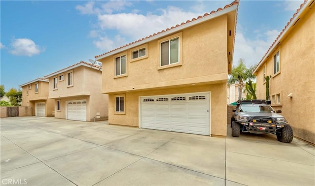 11175 Reagan St, Los Alamitos, CA 90720 - back of house with an attached garage, concrete driveway, a tile roof, and stucco siding