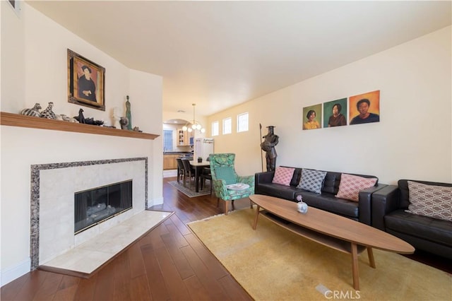 11175 Reagan St, Los Alamitos, CA 90720 - living room featuring visible vents, baseboards, hardwood / wood-style flooring, a tiled fireplace, and a notable chandelier