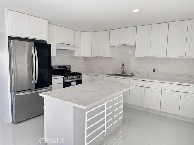 kitchen featuring stainless steel appliances, a sink, under cabinet range hood, tasteful backsplash, and light stone counters