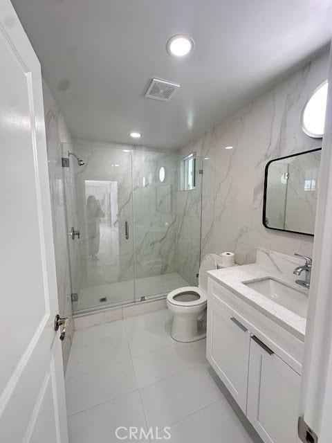 bathroom featuring tile patterned floors, toilet, a marble finish shower, vanity, and recessed lighting