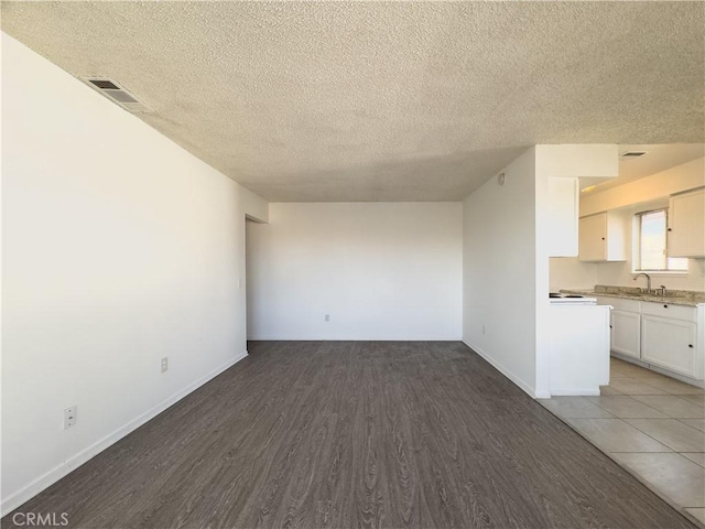 3501 20th St, Highland, CA 92346 - unfurnished living room with a sink, a textured ceiling, baseboards, wood finished floors, and visible vents