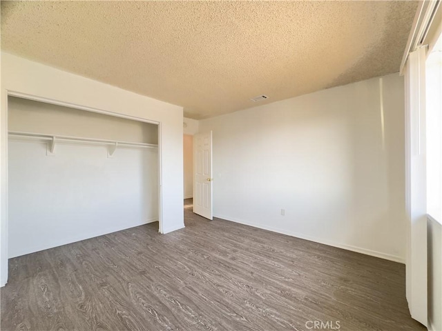 3501 20th St, Highland, CA 92346 - unfurnished bedroom with a closet, visible vents, baseboards, dark wood-style floors, and a textured ceiling