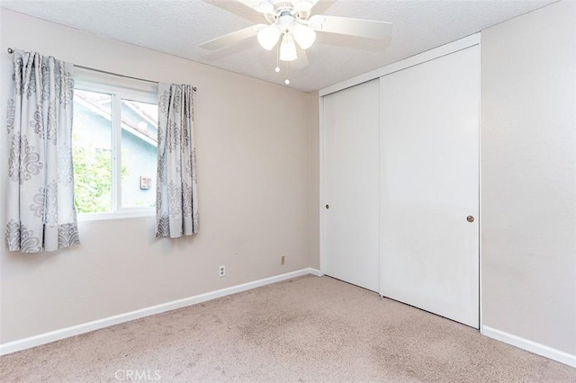 empty room with a textured ceiling, baseboards, ceiling fan, and carpet floors
