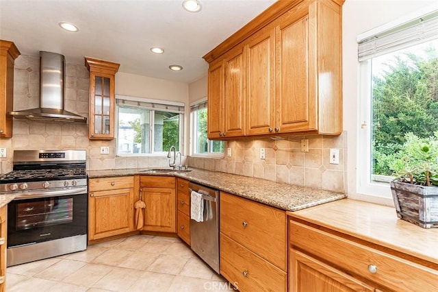 kitchen featuring a sink, appliances with stainless steel finishes, plenty of natural light, and wall chimney exhaust hood