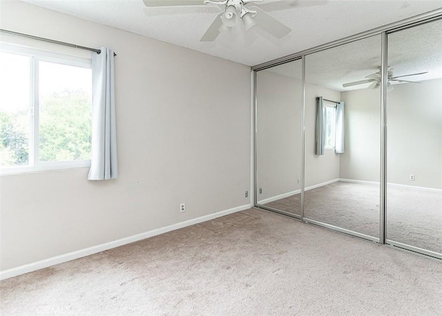 unfurnished bedroom featuring carpet flooring, ceiling fan, a textured ceiling, baseboards, and a closet