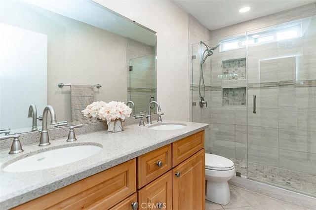 full bath with a sink, tile patterned floors, a shower stall, and toilet