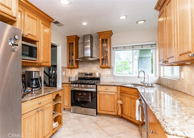 kitchen with visible vents, decorative backsplash, wall chimney exhaust hood, a sink, and appliances with stainless steel finishes