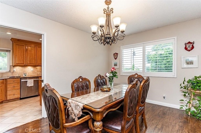 dining space featuring baseboards, a wealth of natural light, light wood-style flooring, and a chandelier