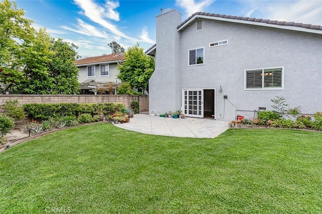 rear view of property featuring a lawn, a patio area, fence, and a chimney