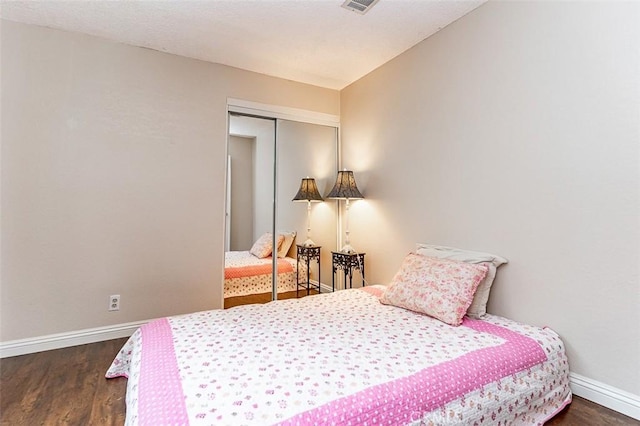 bedroom with baseboards, a closet, dark wood-style flooring, and visible vents