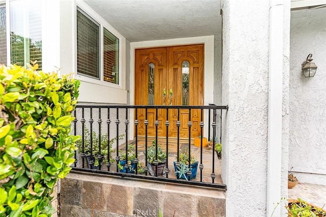 view of exterior entry with a porch and stucco siding