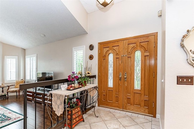 foyer with a textured ceiling and vaulted ceiling