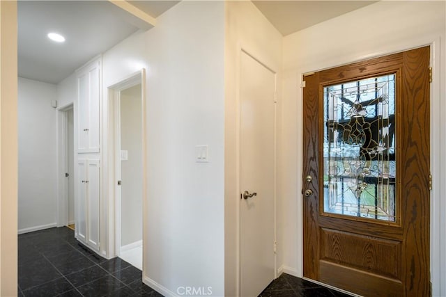 foyer entrance with baseboards and dark tile patterned floors