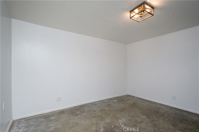 spare room with baseboards and unfinished concrete flooring