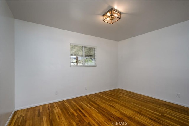 unfurnished room with baseboards and wood finished floors