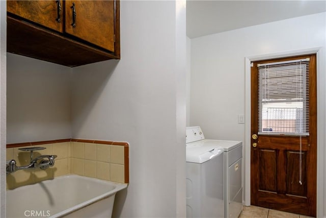 clothes washing area with a sink, cabinet space, light tile patterned flooring, and independent washer and dryer