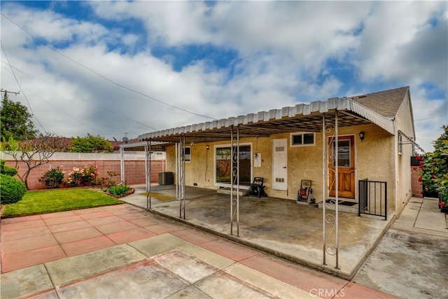 rear view of house featuring a patio, stucco siding, central air condition unit, and fence