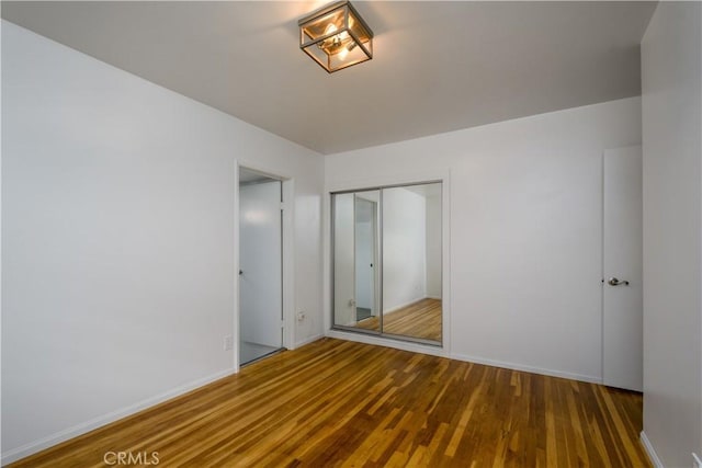 unfurnished bedroom with baseboards, wood finished floors, and a closet