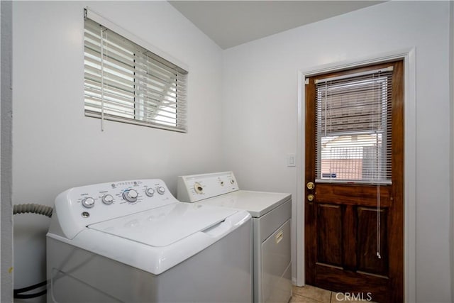 clothes washing area featuring a healthy amount of sunlight, laundry area, washing machine and dryer, and light tile patterned flooring