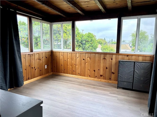 unfurnished sunroom with plenty of natural light, wood finished floors, and wooden walls