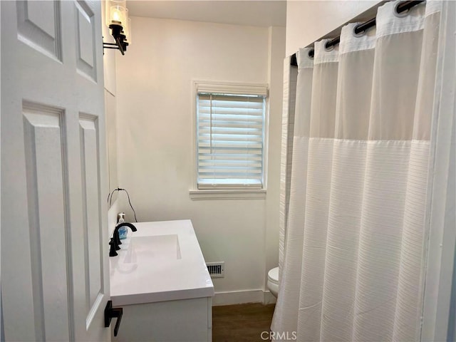 full bathroom featuring visible vents, vanity, wood finished floors, toilet, and baseboards