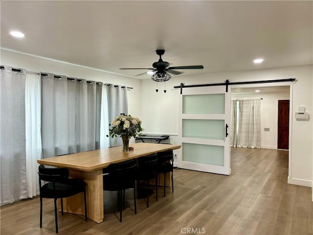 dining area featuring ceiling fan, a barn door, recessed lighting, baseboards, and wood finished floors