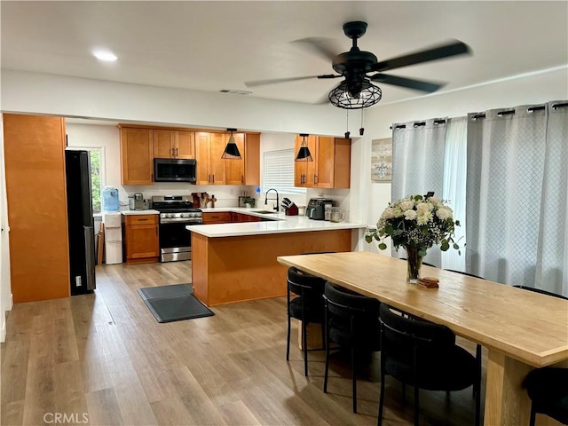 kitchen with brown cabinets, light countertops, stainless steel appliances, a peninsula, and visible vents