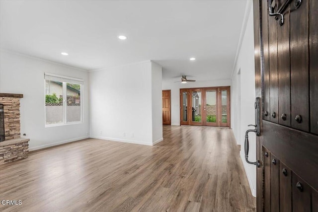unfurnished living room with ornamental molding, a fireplace, light wood finished floors, a ceiling fan, and baseboards