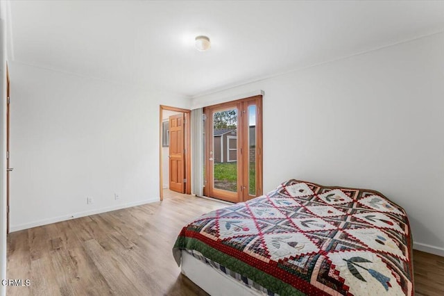 bedroom with access to outside, baseboards, and wood finished floors